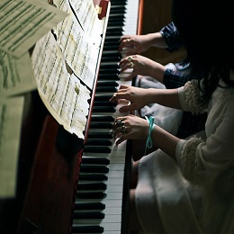 Lady teaching her pupil how to play the piano